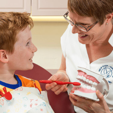 a doctor shows a young patient how to clean his teeth